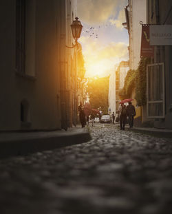 People walking on sidewalk in city against sky