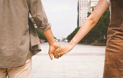 Midsection of couple holding hands