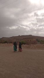 Rear view of couple on field against sky