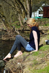 Side view of woman sitting by lake