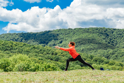 Full length of woman exercising on field against sky