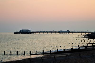 Pier over sea against sky during sunset
