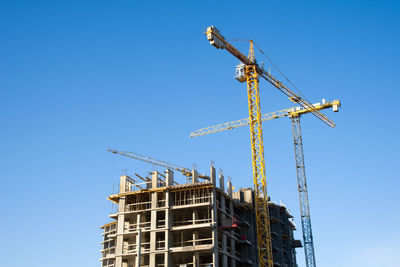 Low angle view of crane against clear blue sky