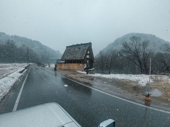 Road by snow covered landscape during rainy season