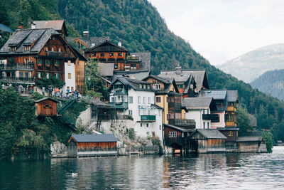 Houses by river against mountains and sky in city
