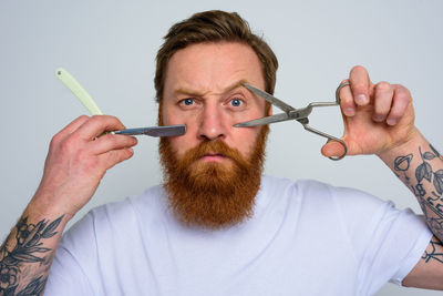 Portrait of man holding eyeglasses against white background