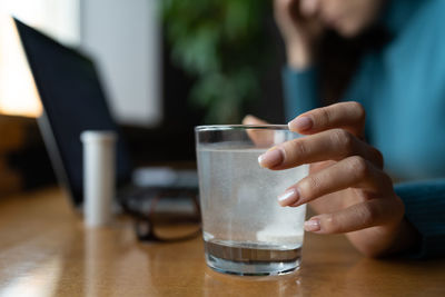 Woman feel sick in office wait for pill tablet dissolving in water glass. ill female take medication