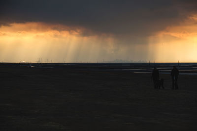 Silhouette people on beach against sky during sunset