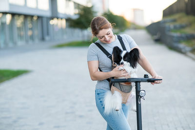 Portrait of young woman with dog on street