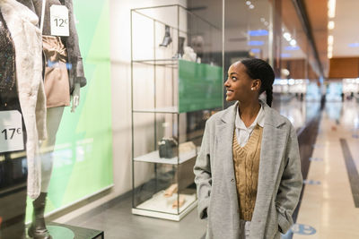 Smiling teenage girl window shopping in mall