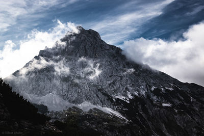 Low angle view of snowcapped mountains against sky