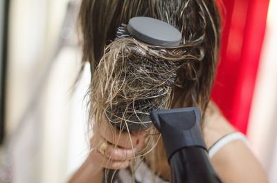 Close-up of woman drying hair with dryer