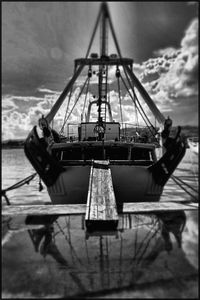 Ship moored at harbor against sky