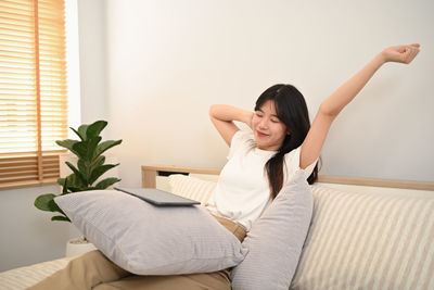 Young woman using mobile phone while lying on bed at home