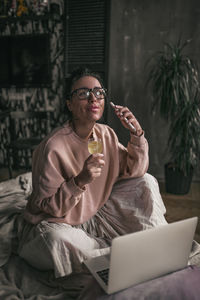 Young woman using mobile phone while sitting in laptop