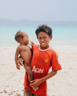 Portrait of happy boy standing on beach against clear sky