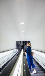 Side view of woman standing on escalator