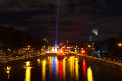 Illuminated bridge over river in city at night