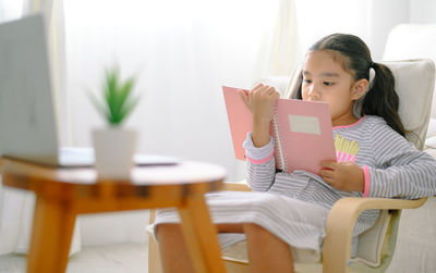 Girl using mobile phone while sitting in laptop