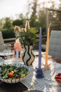 Candles kept near salad bowl on table during party in back yard