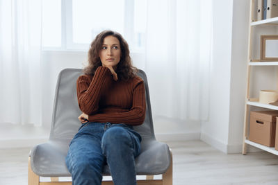 Portrait of young woman sitting on sofa at home