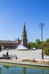 People walking on street by building against clear blue sky