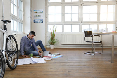 Man using laptop on the floor in a modern informal office