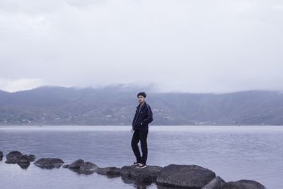 Full length of man standing on rock against sky