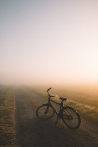 Bicycle on field against sky during sunset