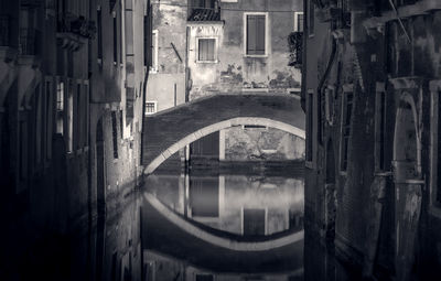 Arch bridge over canal amidst buildings in city