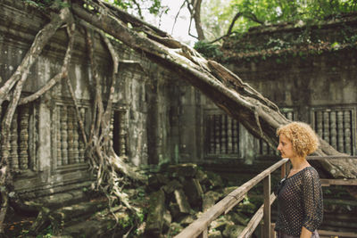 Side view of woman at old ruins in forest