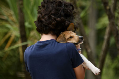 Rear view of boy hugging his dog