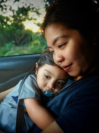 Side view of smiling mother holding boy in car
