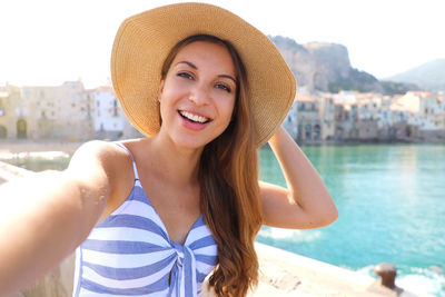 Portrait of smiling young woman in hat standing outdoors