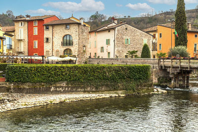 Buildings by river against sky