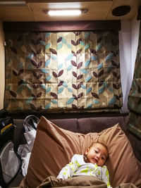 Portrait of cute baby girl lying on pillow at motor home