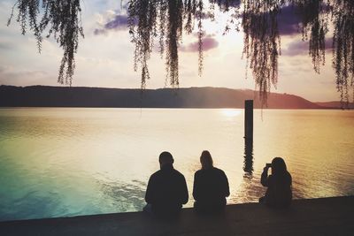 Silhouette men on water at sunset