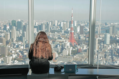 Person sitting looking at city through window