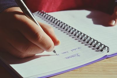 Close-up of hand writing on book