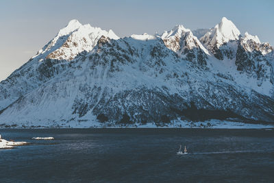 Scenic view of sea and snowcapped mountains against sky