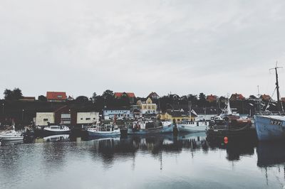 Boats moored at harbor against sky