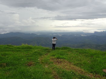 Rear view of man standing on mountain against sky