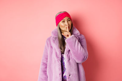 Woman standing against pink background