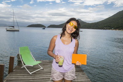 Woman holding drink on pier at the tropical island of ilha grande