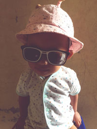 Midsection of baby girl wearing sunglasses standing against wall