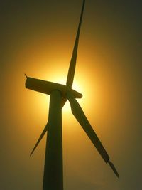 Silhouette of wind turbine against sky during sunset