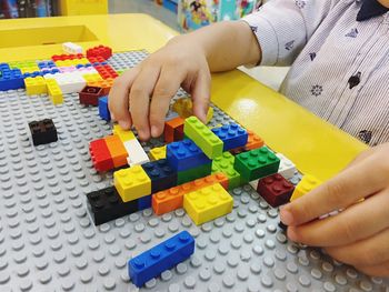 Midsection of girl playing with plastic blocks at home