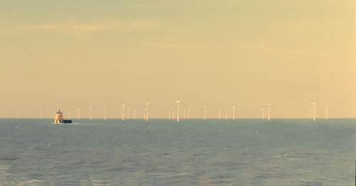 Wind turbines in sea against sky