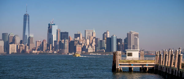 Modern buildings by sea against clear sky