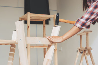 Midsection of woman standing on table at home